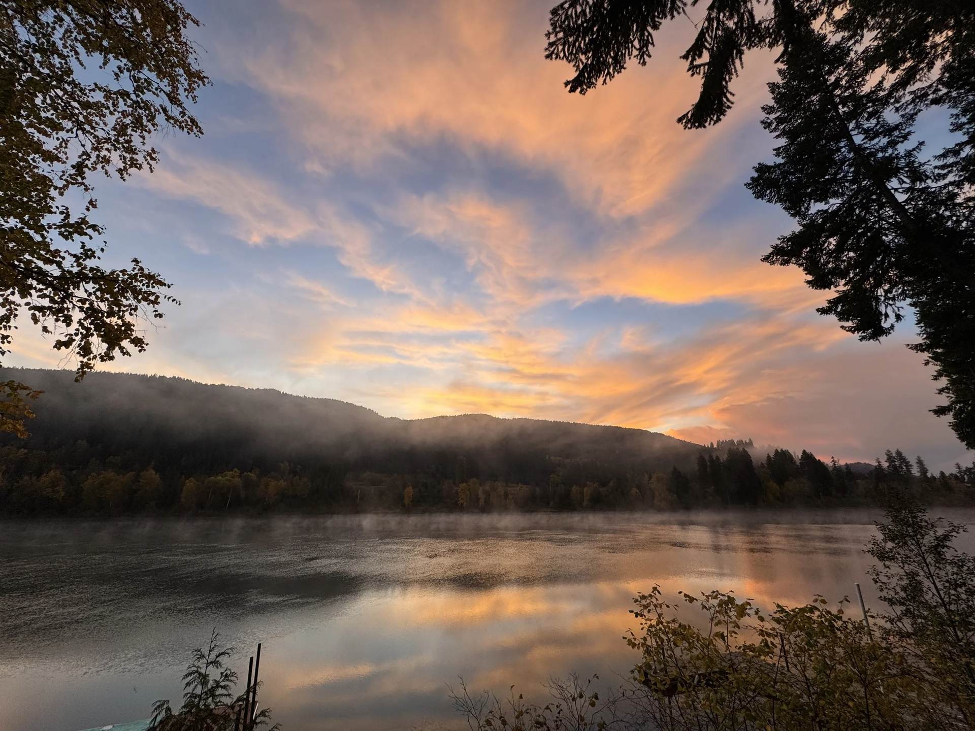 Sunrise over the Pend Oreille River, gold clouds above a dark ridge and still water